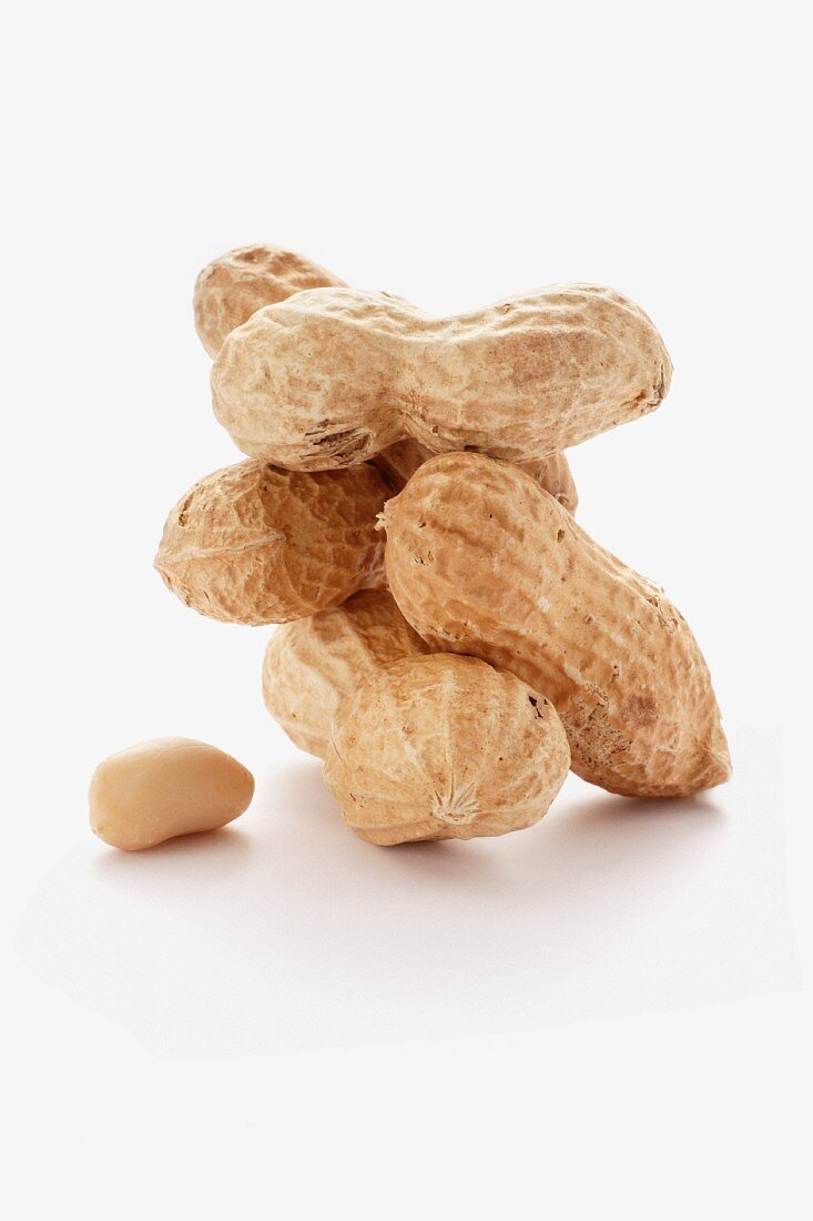 Several whole peanuts and a shelled peanut