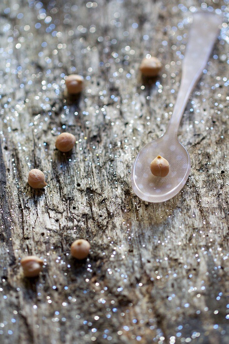 Dried chickpeas on a spoon and on a wooden surface