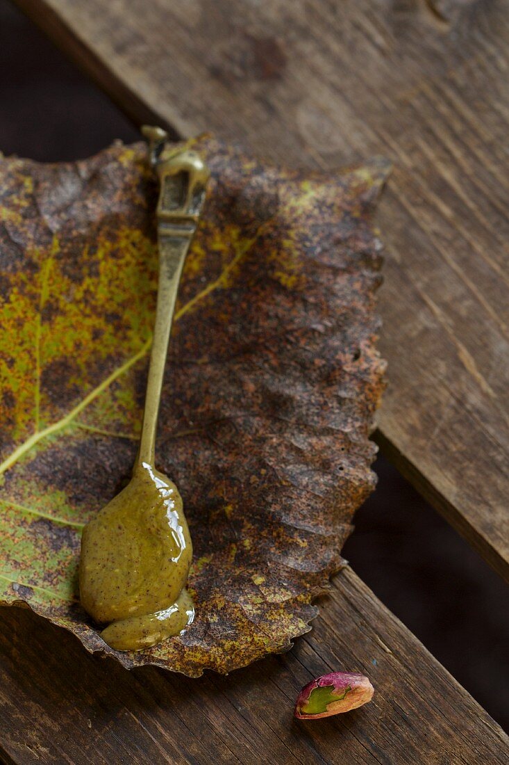 A spoonful of pistachio sauce on an autumn leaf