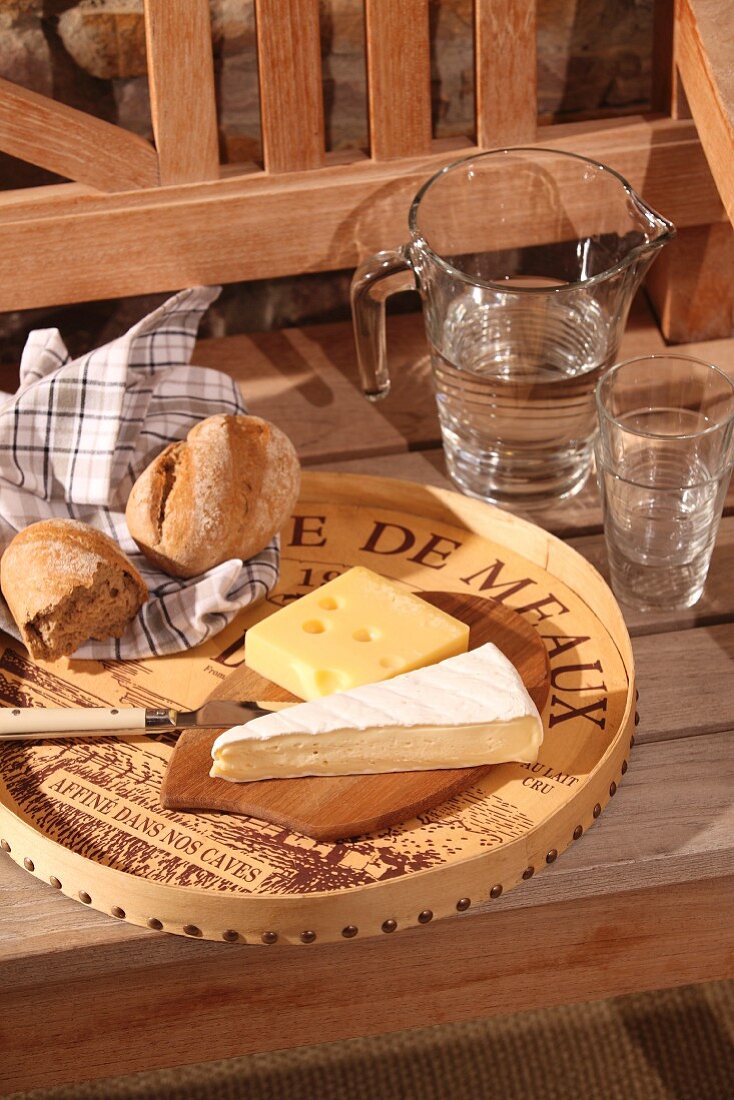Cheese board upcycled from old wine crate with chip wood edge; carafe of water and glasses on wooden bench
