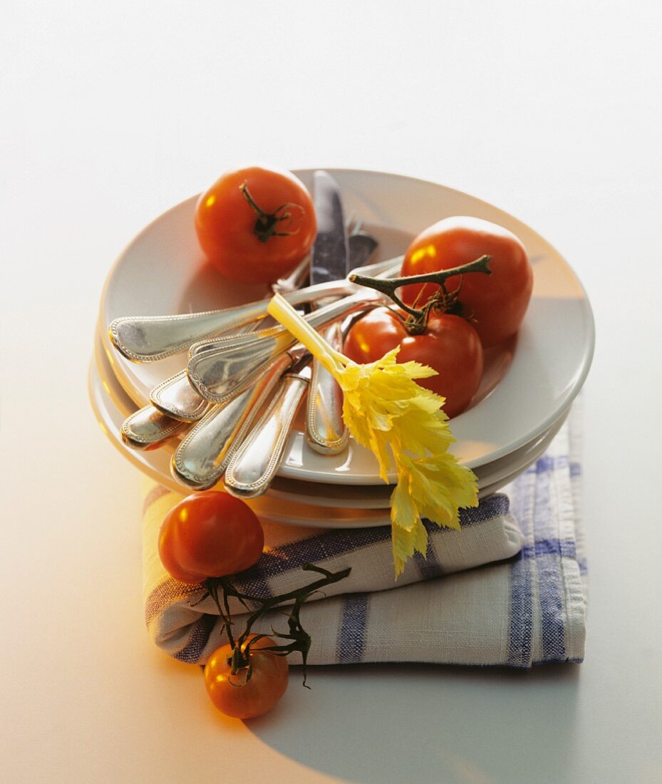 A stack of plates with cutlery and tomatoes