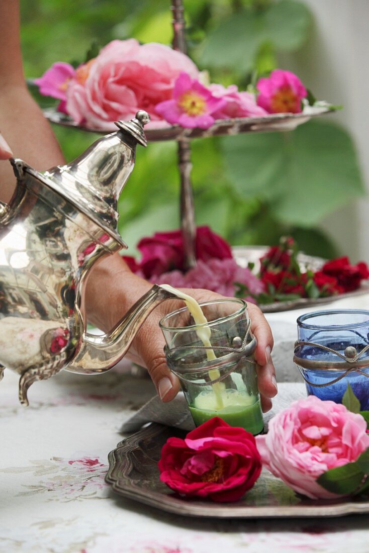 Einen Rosen-Schlaftrunk in silberverzierte Teegläser eingiessen