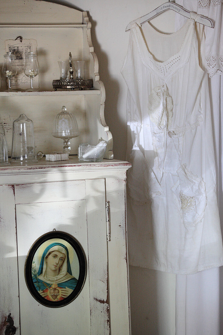 Old slip hung next to cabinet with picture of Madonna on door