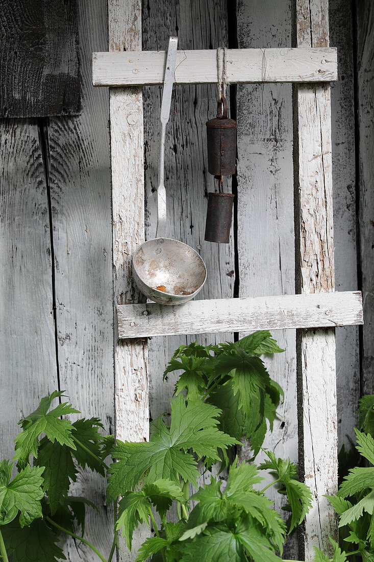 Ladle and metal bell on ladder in front of board wall