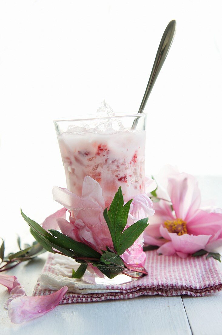 A glass of strawberry milk and peonies