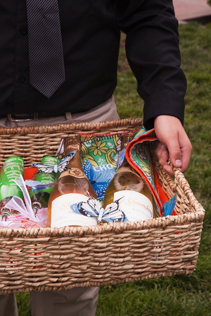 A Man holding a Basket with Champagne and Glasses