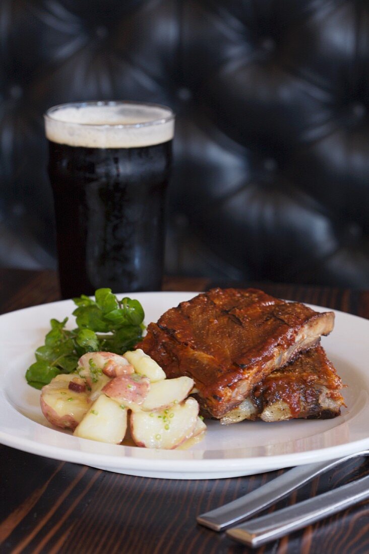 A Plate of Ribs and Potato Salad with a Pint of Beer