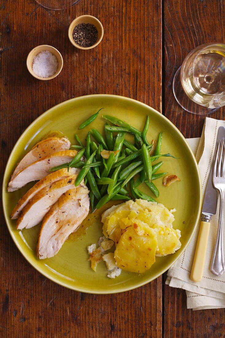 A Plate of Sliced Roast Chicken, Green Beans and Potato Gratin