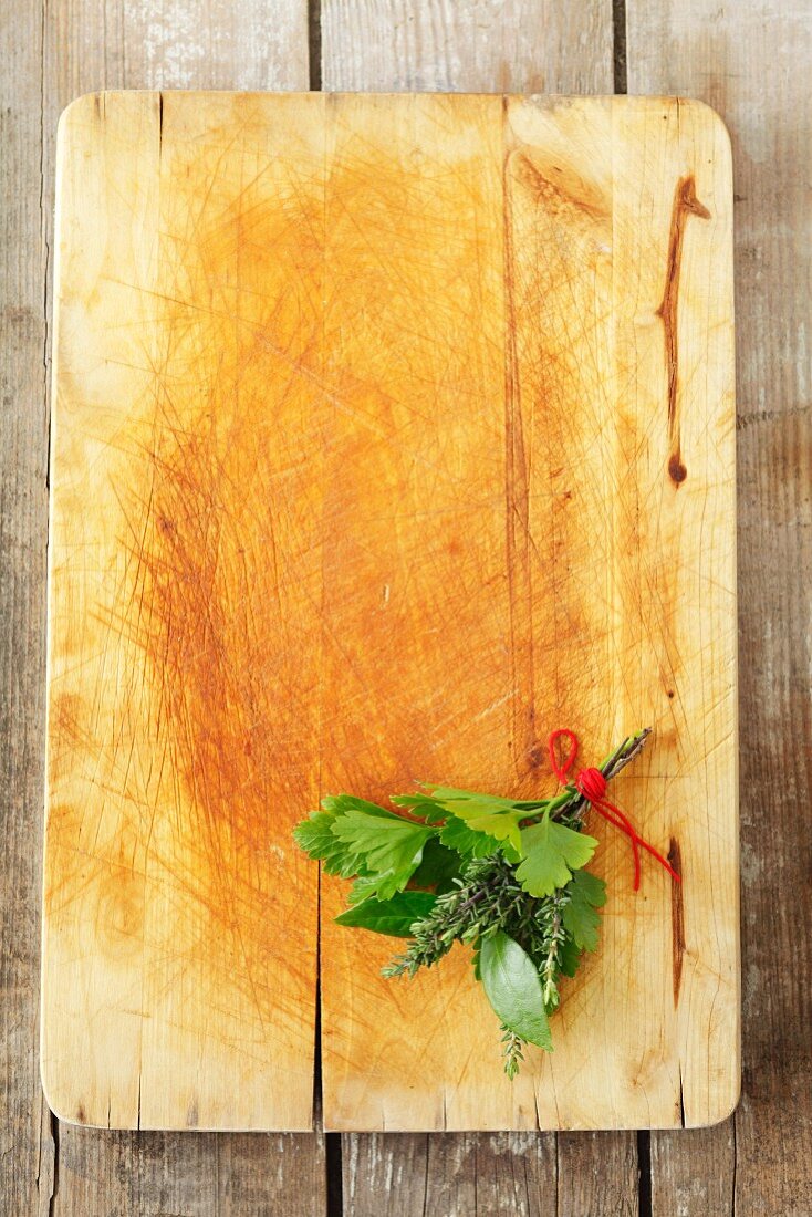 A bouquet of herbs, with parsley, bay and thyme, on a chopping board