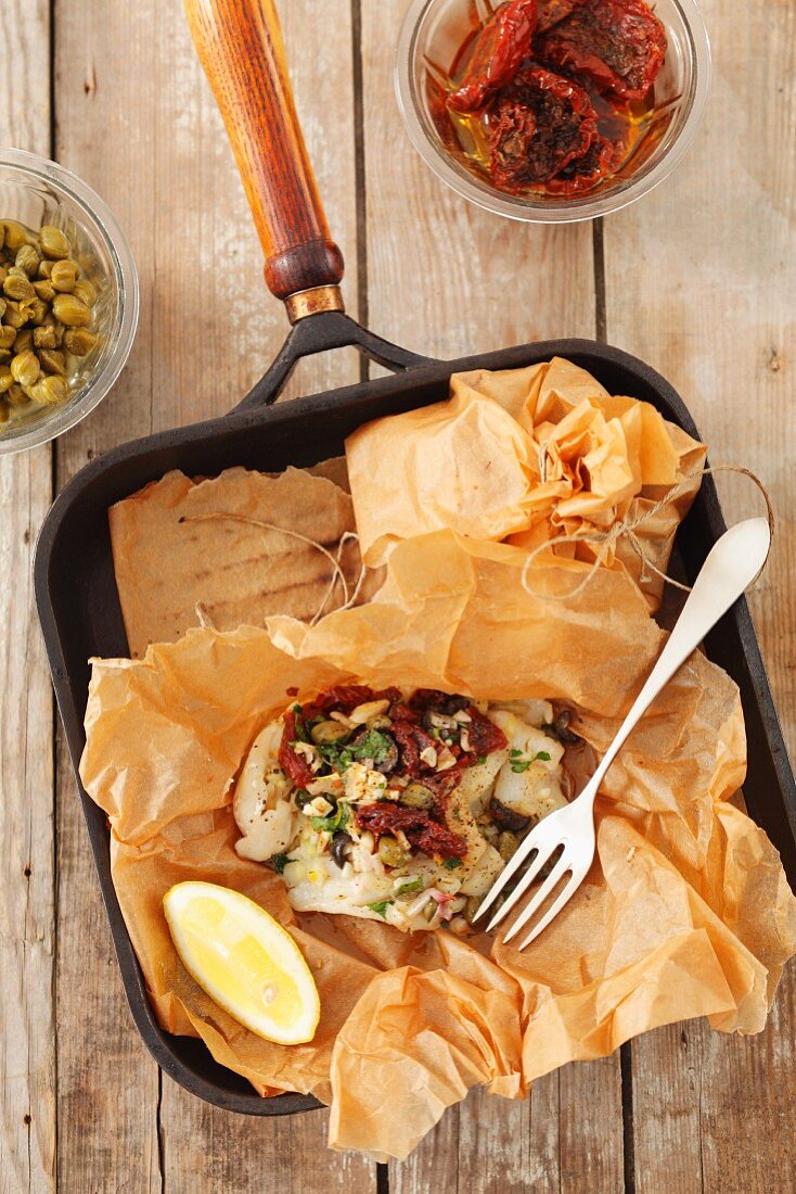Fish in baking parchment with sundried tomatoes and capers