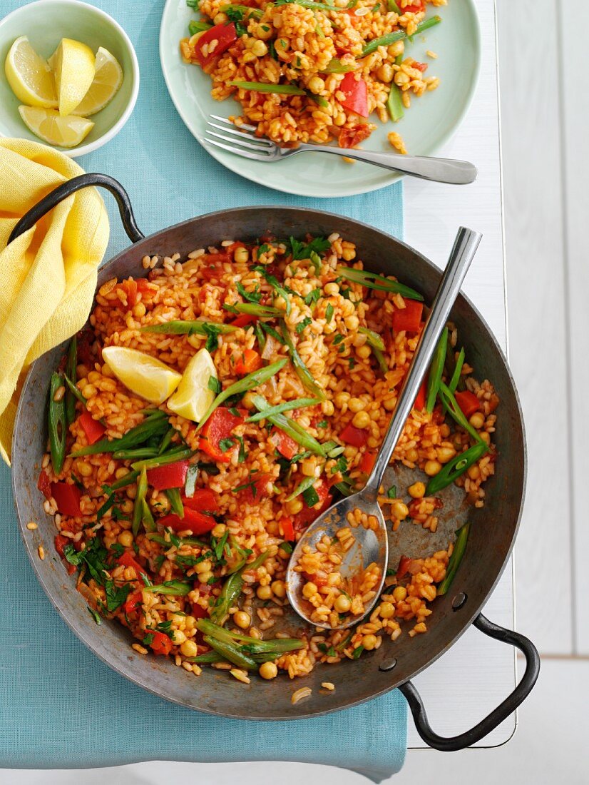 Gemüse-Paella in Pfanne und auf Teller