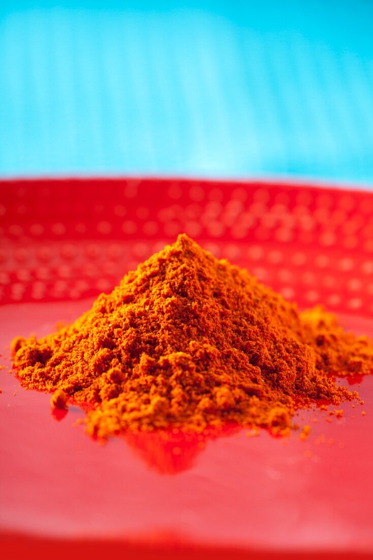 A mound of ground paprika on a red plate