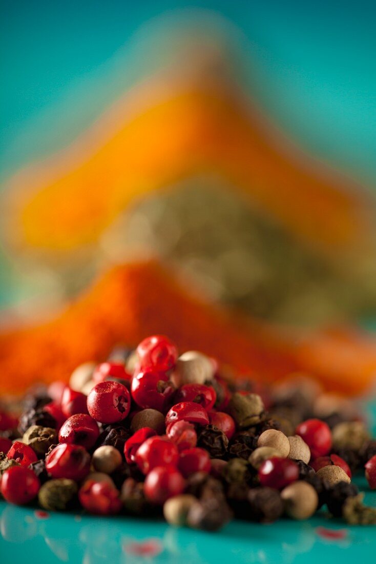 Mixed peppercorns in front of assorted spices