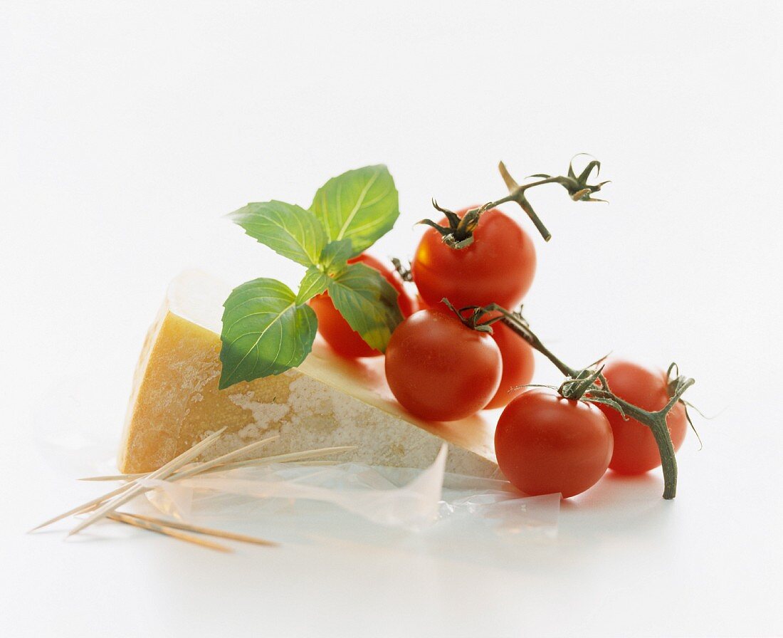 A still life featuring cheese, tomatoes and basil