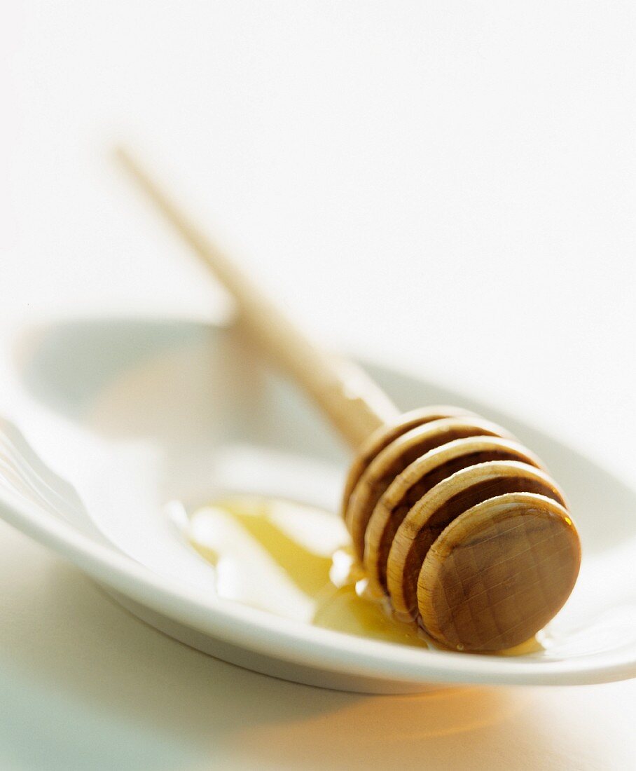 A honey dipper with honey on a plate