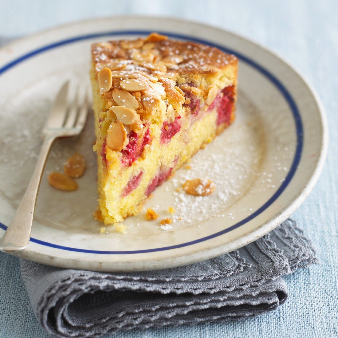 A slice of raspberry cake with flaked almonds