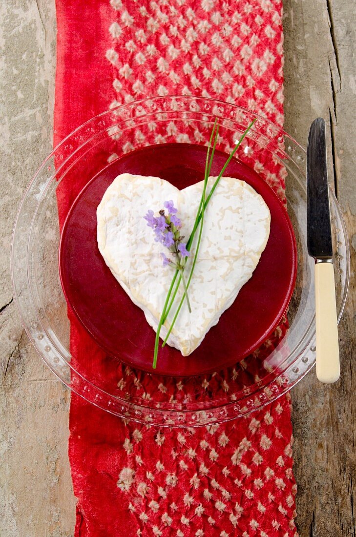 A heart-shaped Neufchatel cheese with a sprig of lavender on a red and white silk cloth