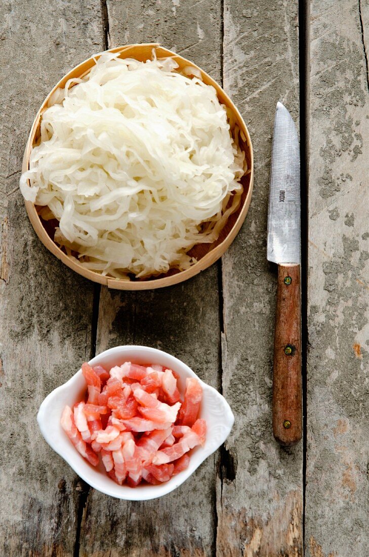 Fresh sauerkraut from Alsace in a wooden dish, lardons of bacon and a rustic knife