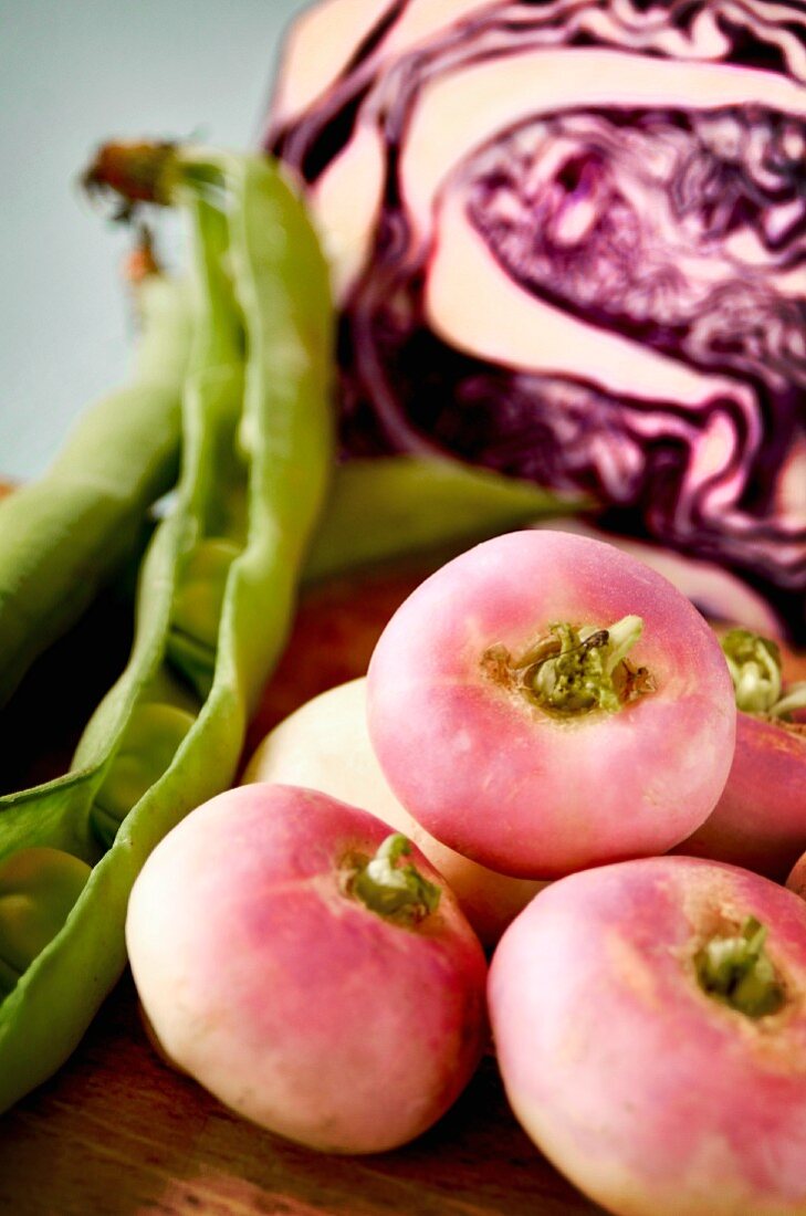 White turnips, red cabbage and beans on a wooden board