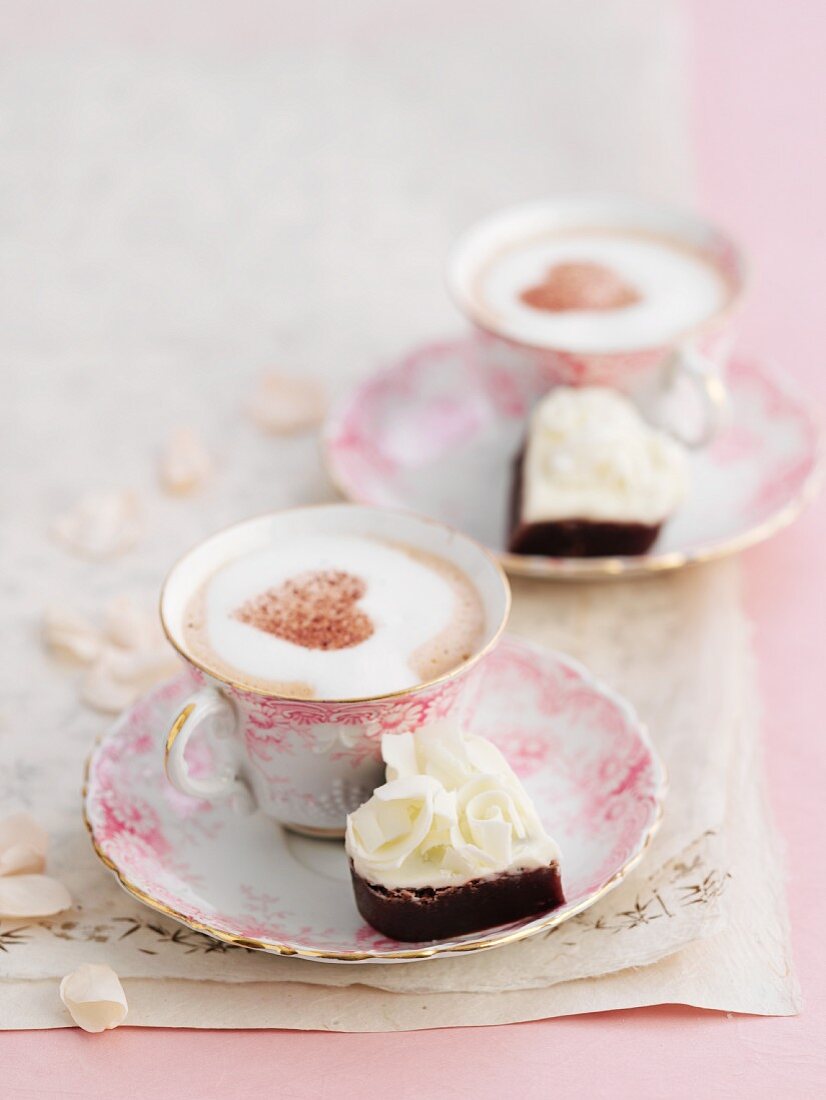 Petit fours and cappuccino decorated with cocoa powder hearts