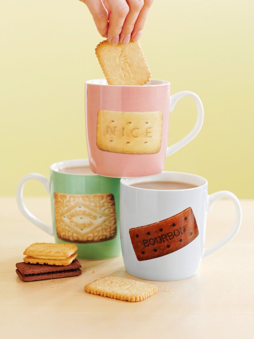 A hand dunking a cookie in a tea mug