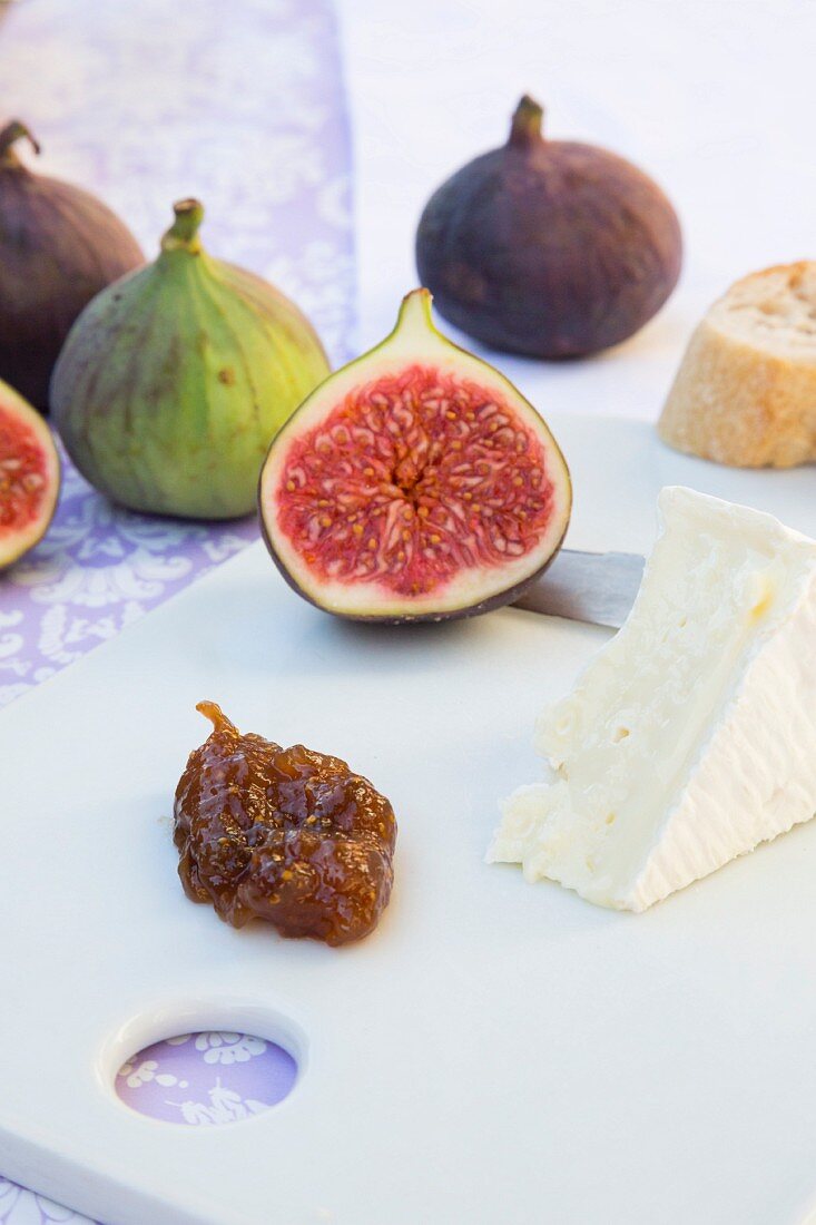Fresh figs, fig pulp, camembert, a knife and a slice of baguette