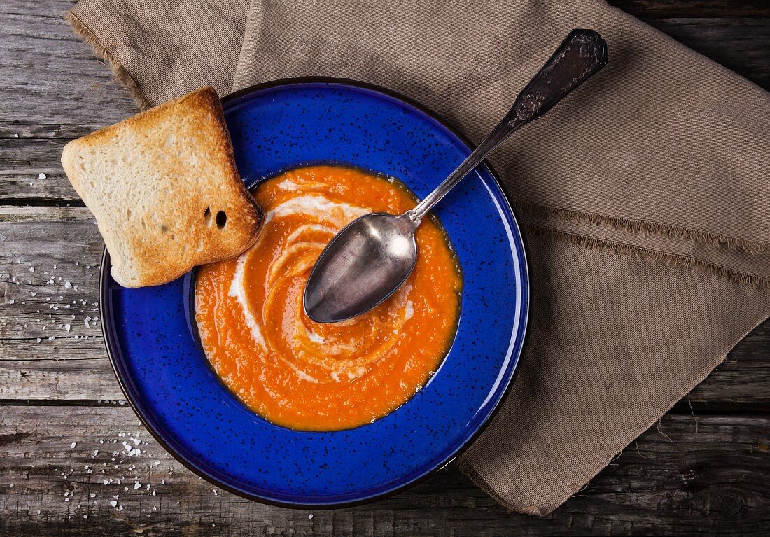 Top view on blue plate of pumpkin puree over old wooden table