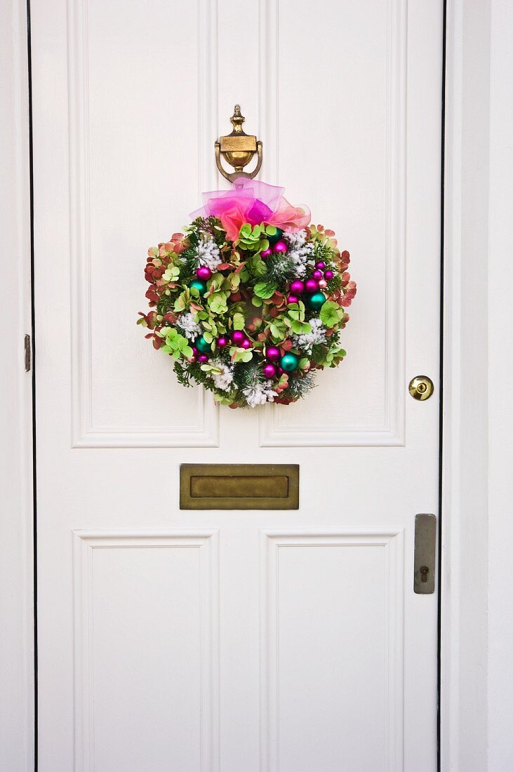 Pink and green dried Hydrangea flower, Christmas wreath on white front door