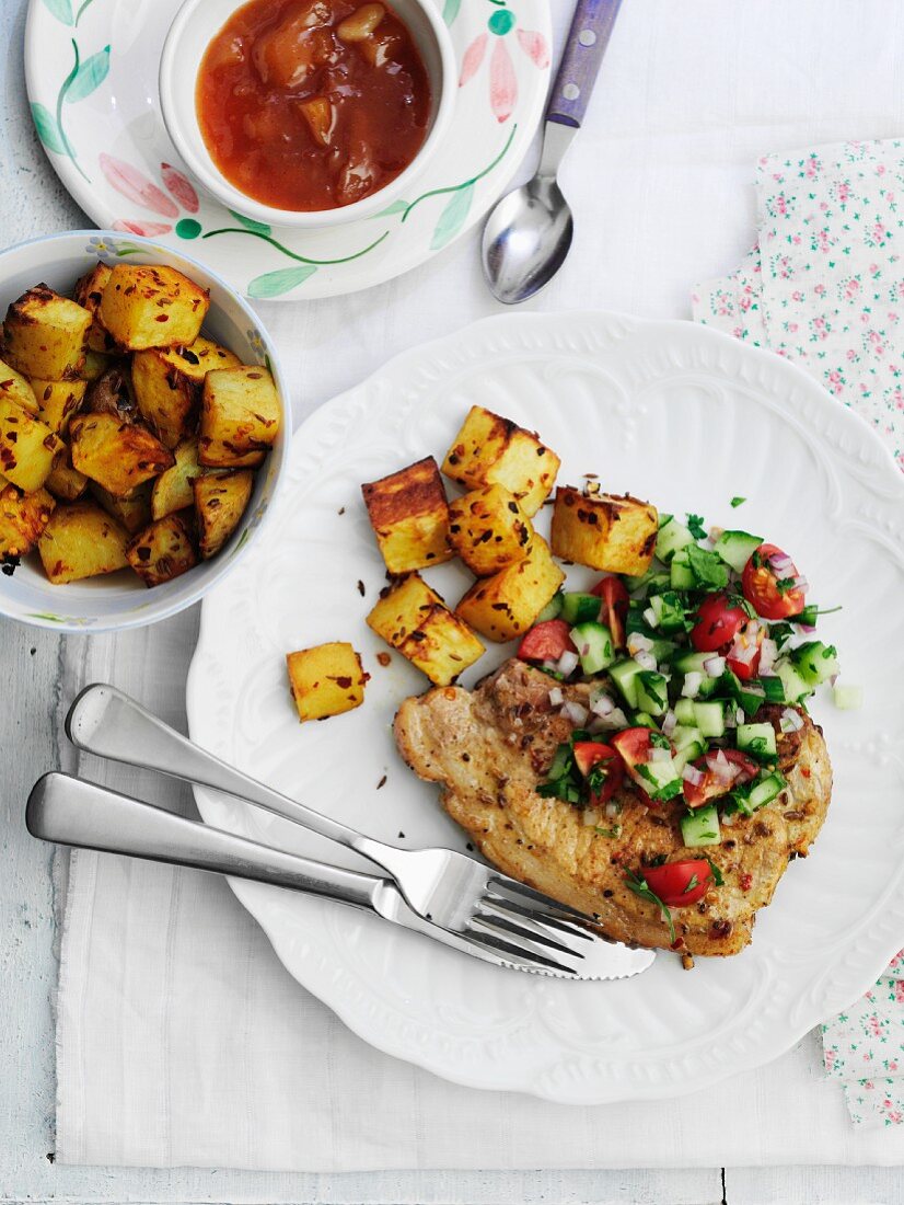 Würziges Schweinekotelett mit Gurken-Tomaten-Salsa, Bratkartoffeln und Chutney (Indien)