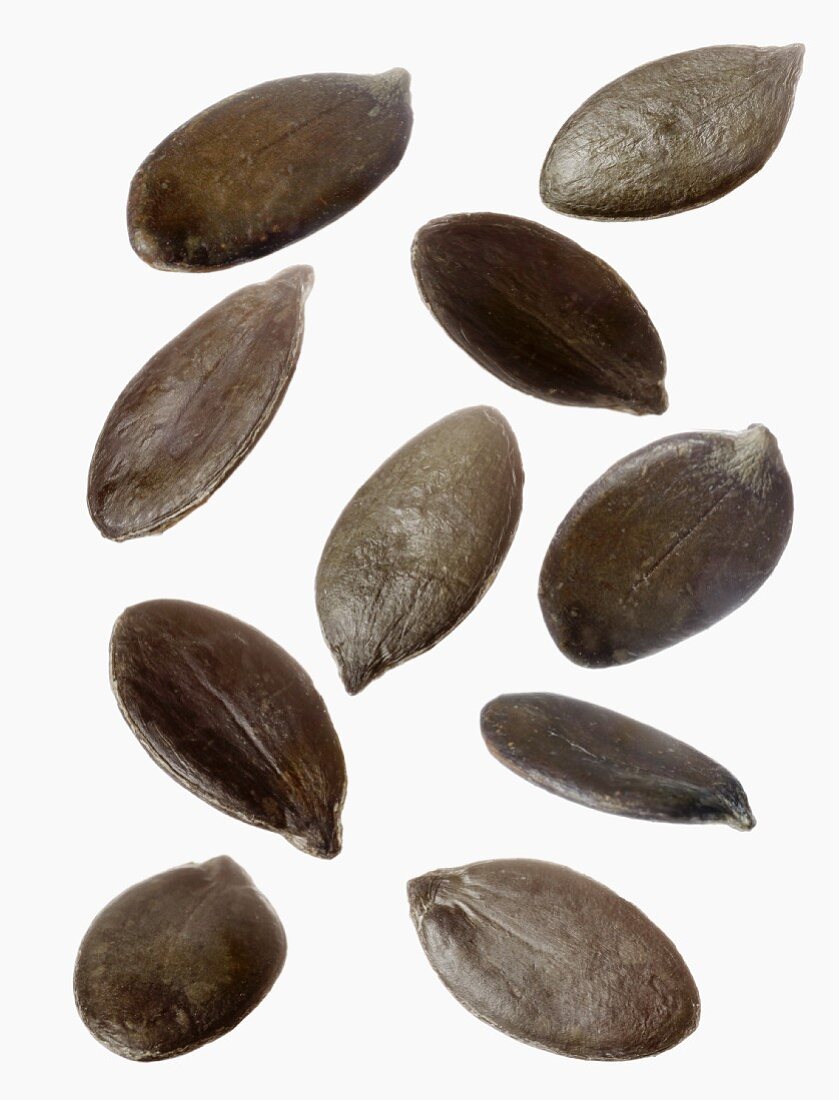 Several pumpkin seeds against a white background