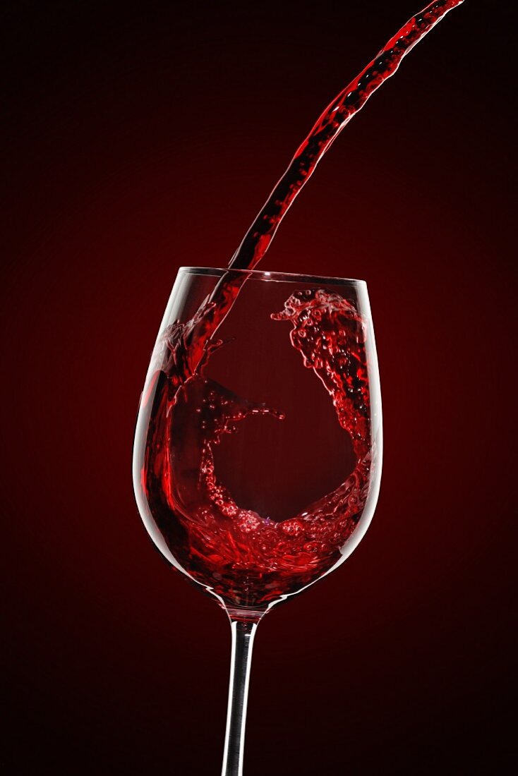 Rotwein wird in Weinglas eingegossen