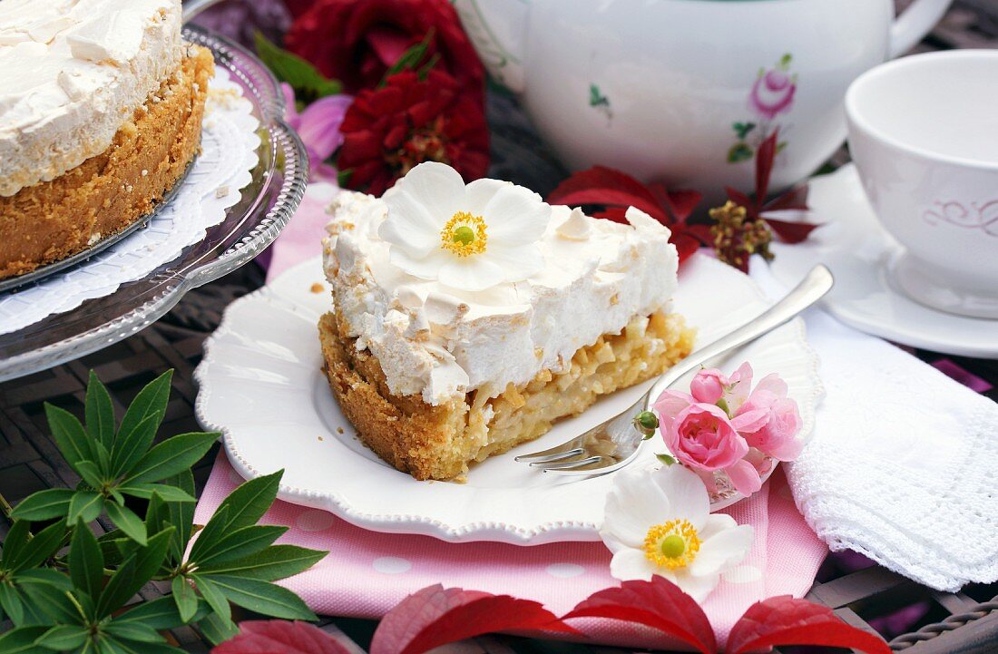 Apple cake with meringue and anemone flowers on a garden table