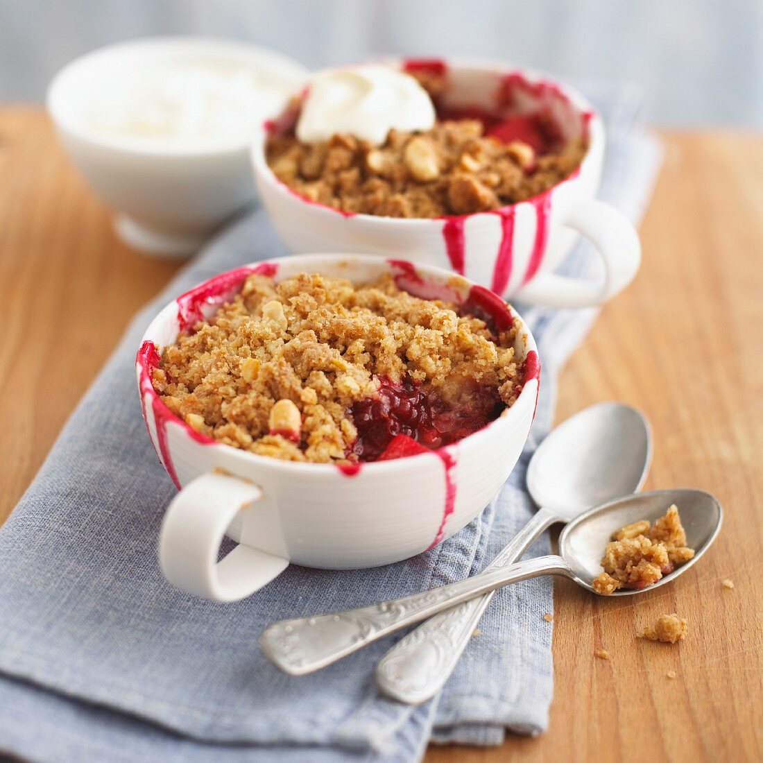Boysenberry-apple crumbles with cream, with a bite taken out of one