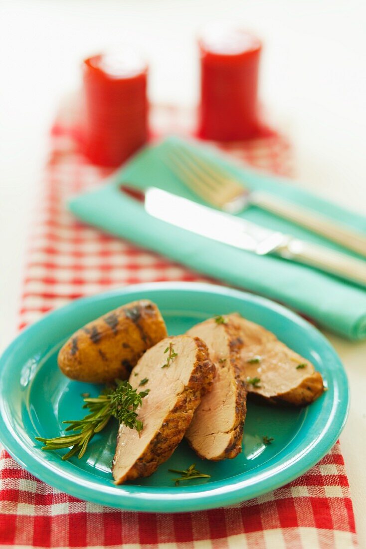 Slices of roast pork with grilled potatoes, rosemary and thyme