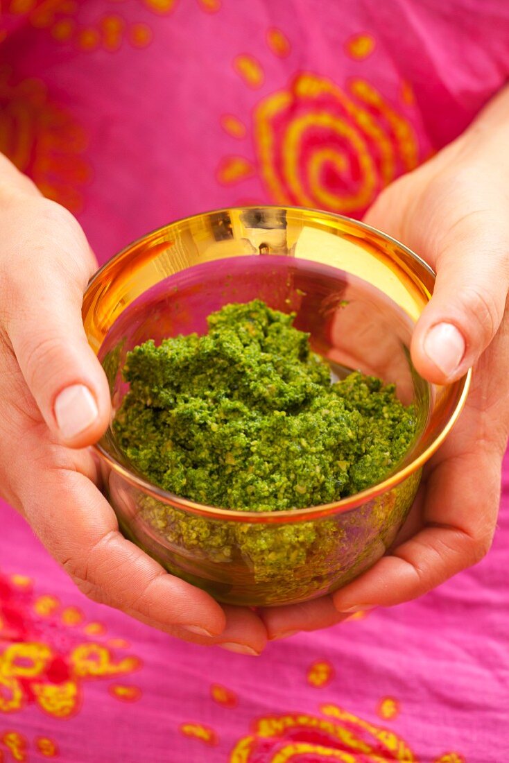 Little girl holding a bowl with pesto