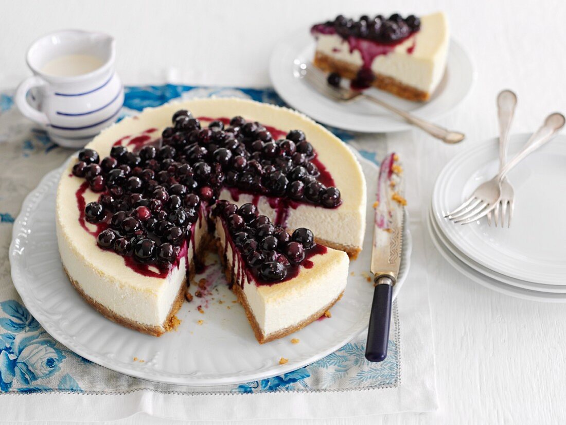 Slice of Blueberry Cheesecake on a Plate, Whole Cheesecake with Slice Removed