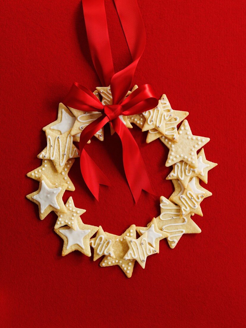 Wreath made of star cookies with a red ribbon in front of a red background