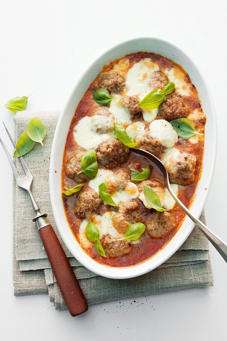 Baked meatballs in tomato sauce with mozzarella and basil