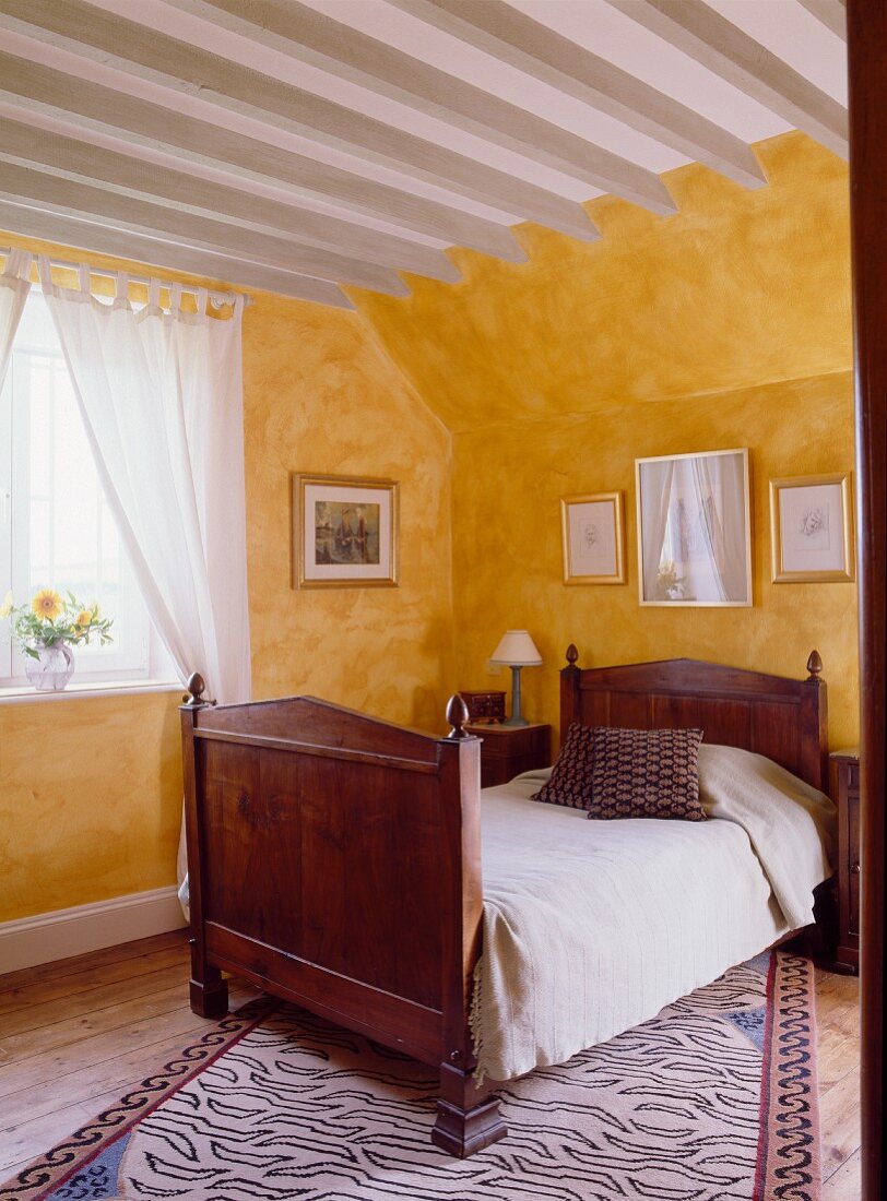 Gästeschlafzimmer im englischen Landhaus mit Holzbett und gelben Wänden