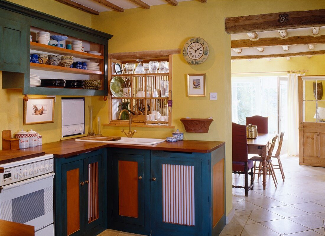 A petrol blue kitchen in an English country house, with a view into the adjacent dining room