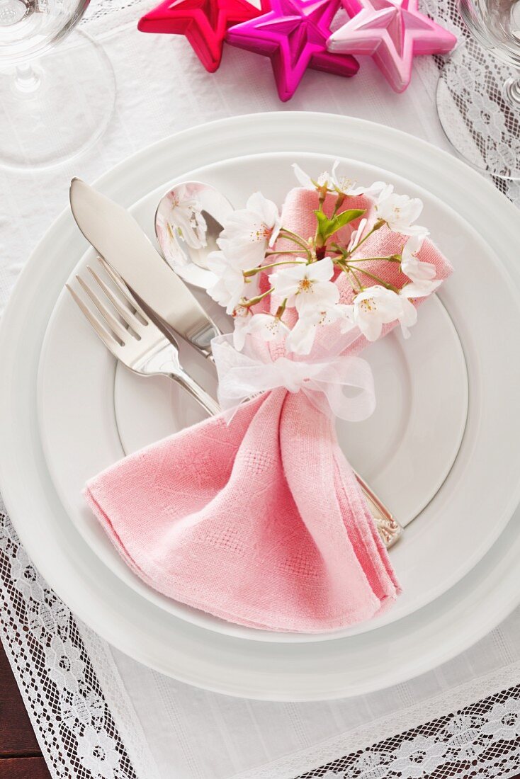 Festliches Gedeck mit rosa Serviette und weißen Blüten