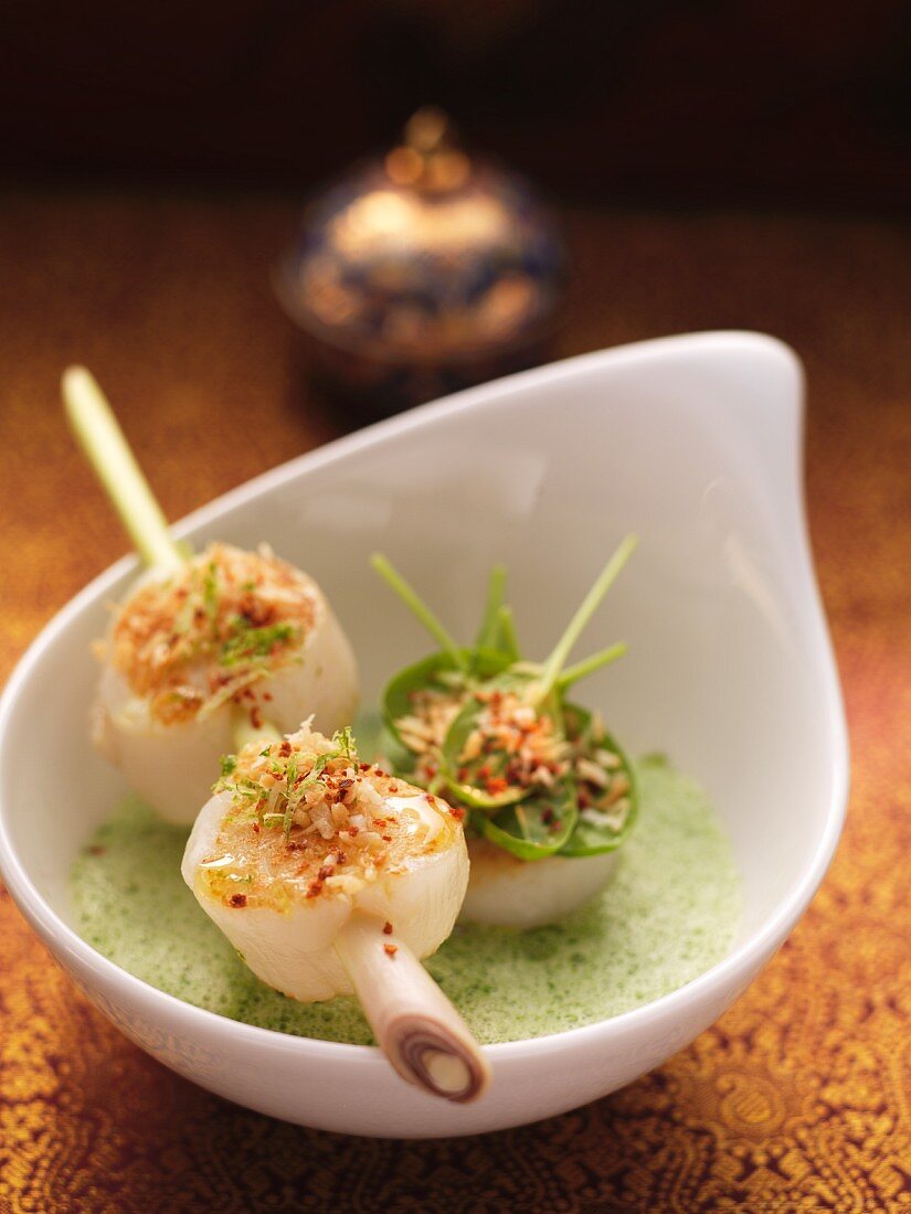 Coconut and spinach soup with fried scallops on a lemongrass skewer