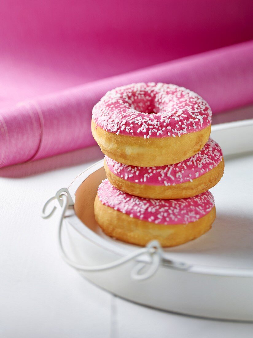 Drei Doughnuts mit rosa Zuckerguss, gestapelt