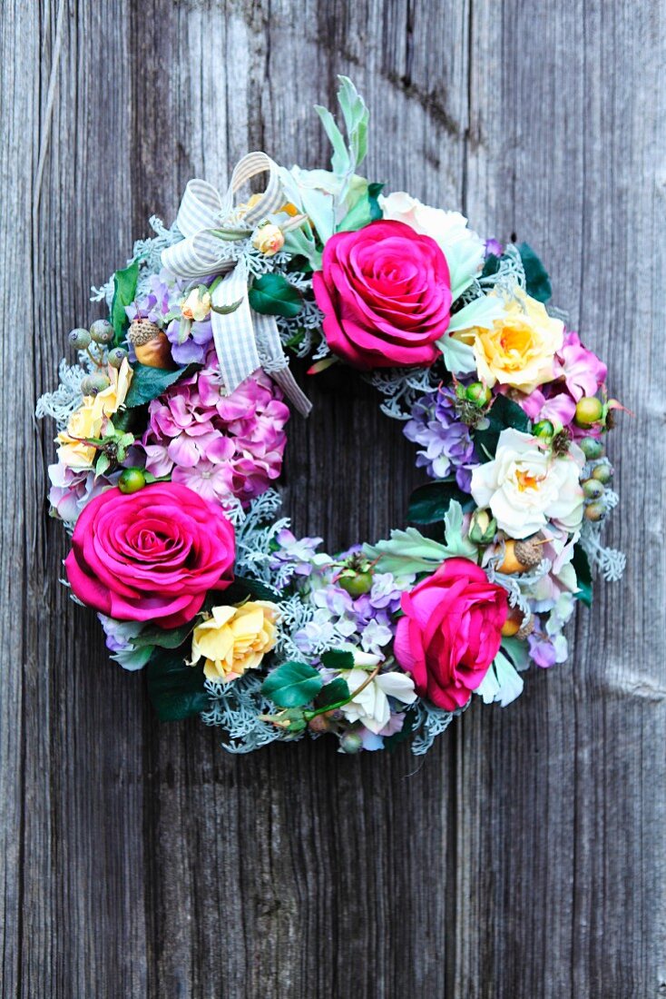 Wreath of flowers and ribbons on wooden wall
