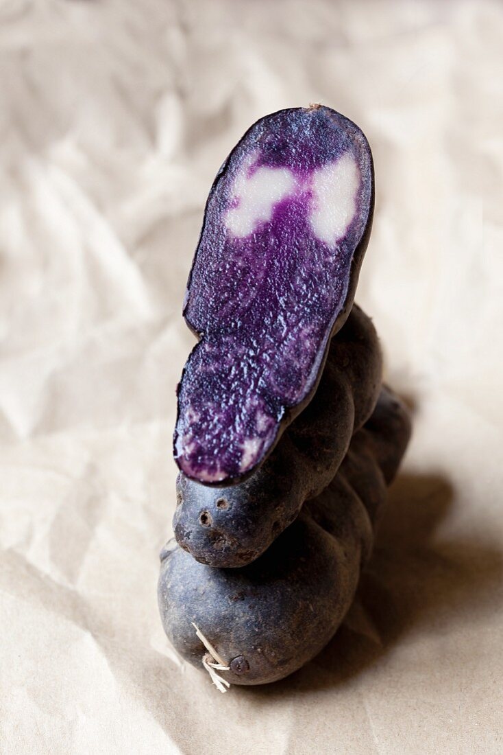 Vitelotte potatoes, whole and cut in half, stacked