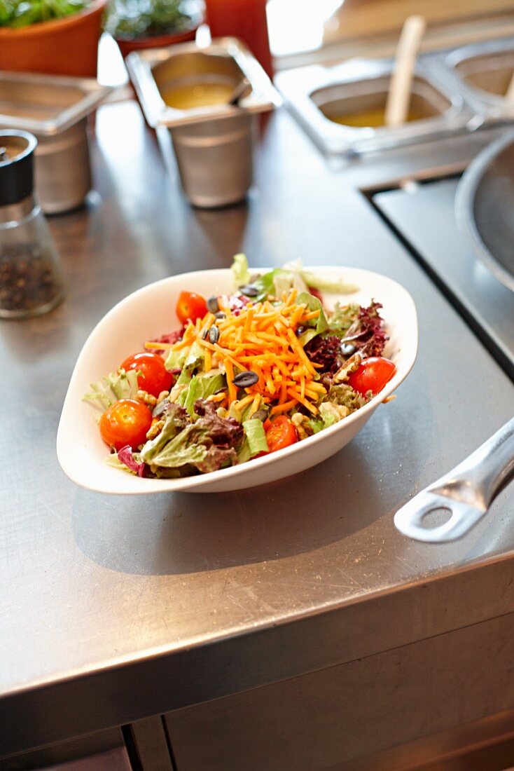 Salad leaves with carrots and tomatoes in a restaurant kitchen