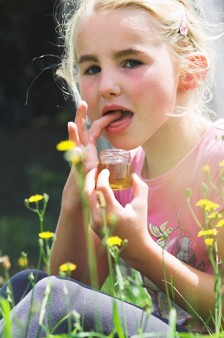 A girl trying freshly bottled wild honey