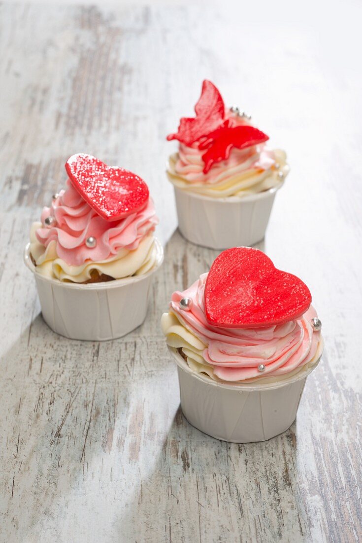 Rosa Cupcakes mit roten Herzen und Schmetterling