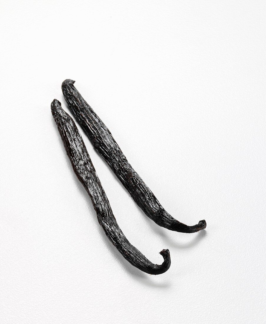 Two vanilla pods against a white background