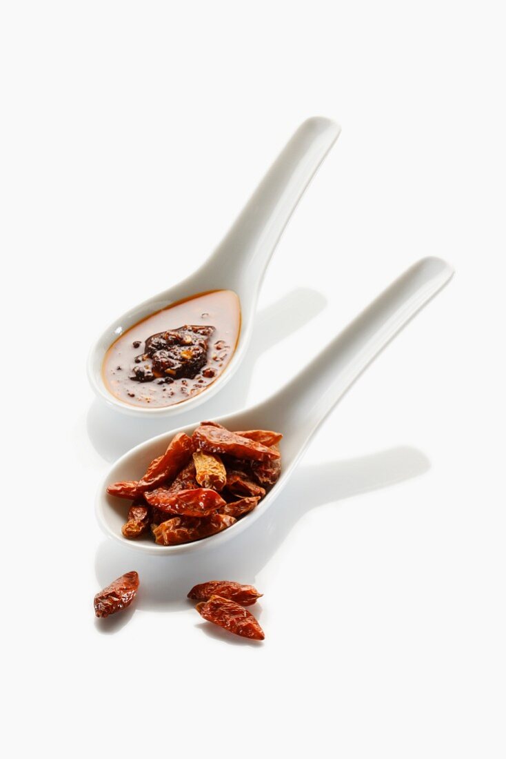 Two spoons with dried chillies and chilli oil